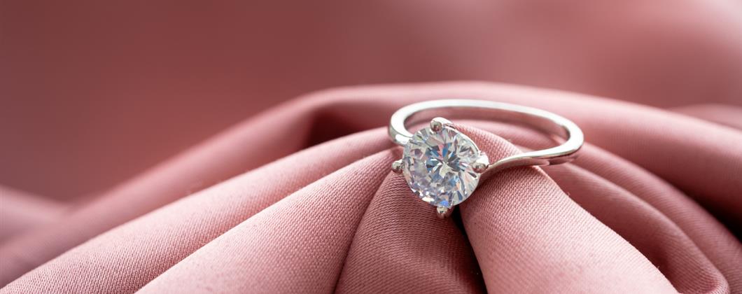 silver diamond ring on a pink cloth